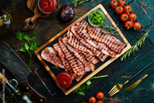 Fried pieces of bacon on a black stone board. Top view. Free space for text.