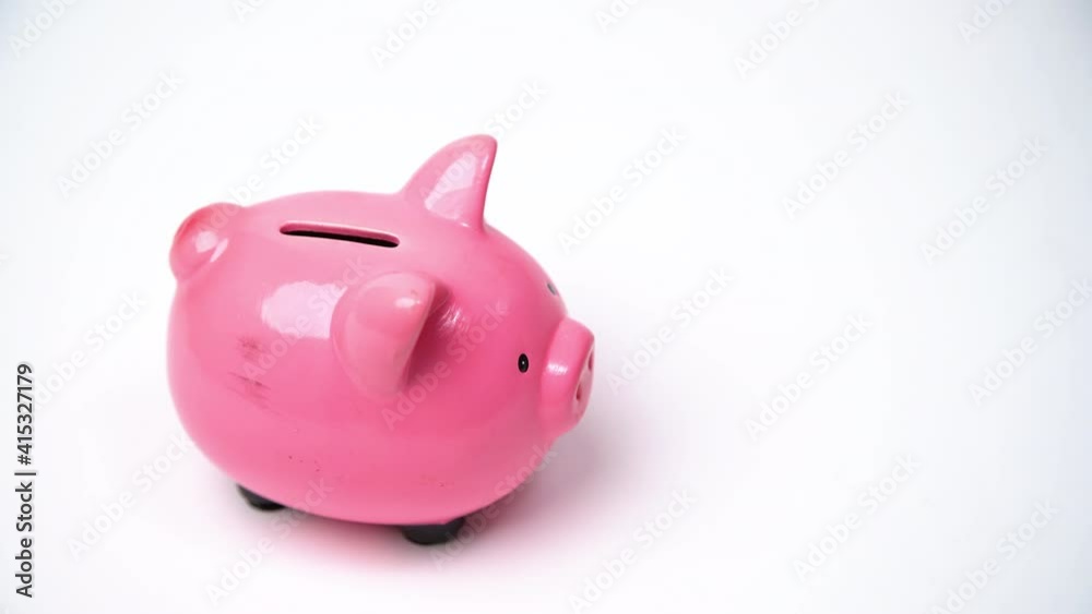 Close up of hand inserting coin into piggy bank. Saving money and financial education concept. Close up of hand inserting coin into piggy bank. Saving money and financial education concept.