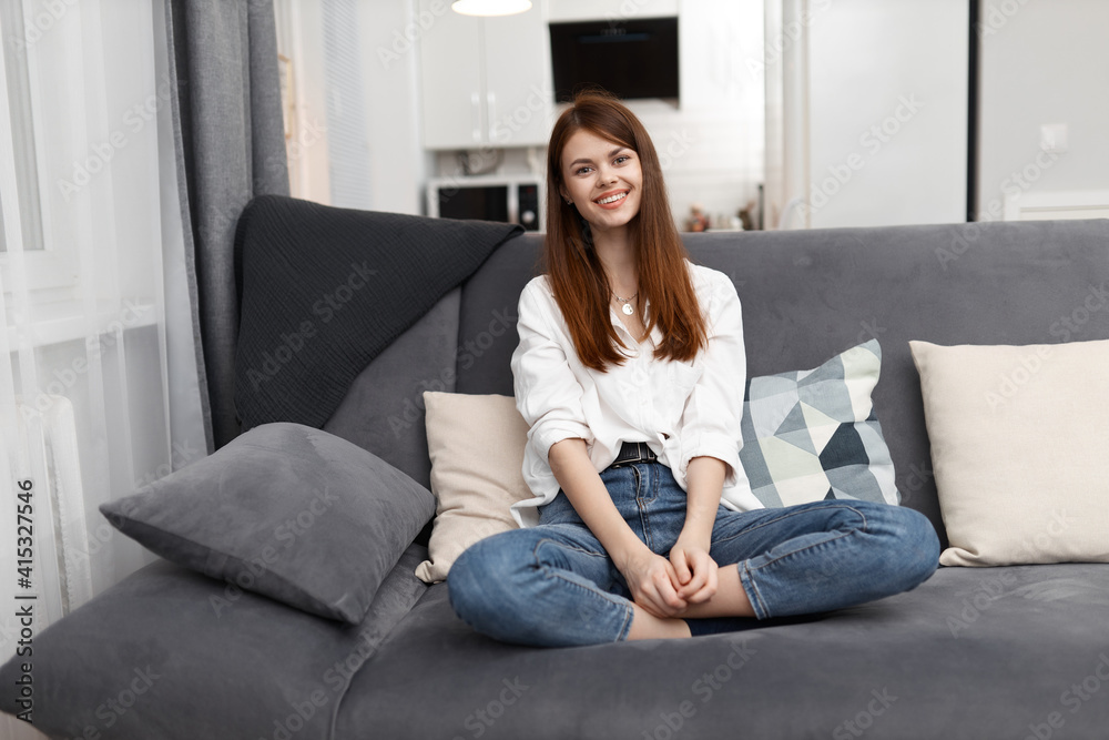 smiling woman sitting on a comfortable sofa in an apartment weekend smiling woman sitting on a comfortable sofa in an apartment weekend