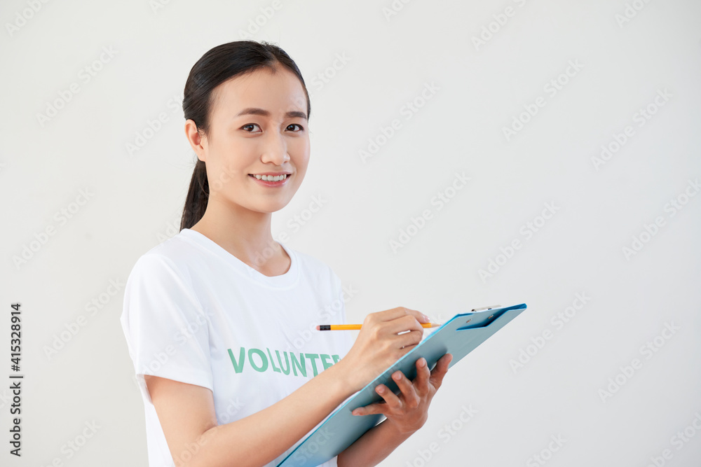 Pretty young Asian woman filling document for volunteer organization she is working for Pretty young Asian woman filling document for volunteer organization she is working for