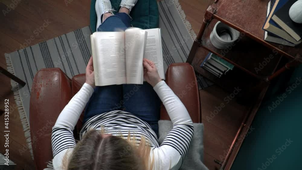 Top down view of young woman reading a book. Slow motion footage of book pages turning backwards and forwards
