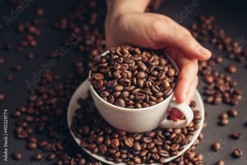 a cup with coffee beans stands on a saucer on a gray background close-up