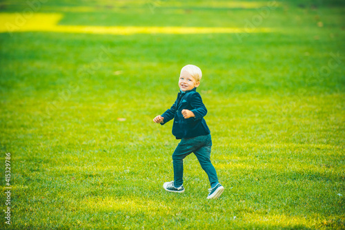 Child boy run in spring or summer field. Kid at park. Childhood activity, leisure, lifestyle concept.