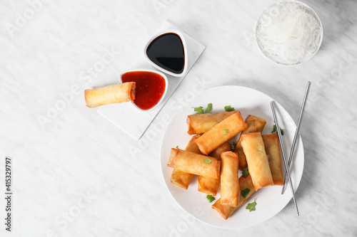 Картината върху платно Plate with tasty fried spring rolls and sauce on light background