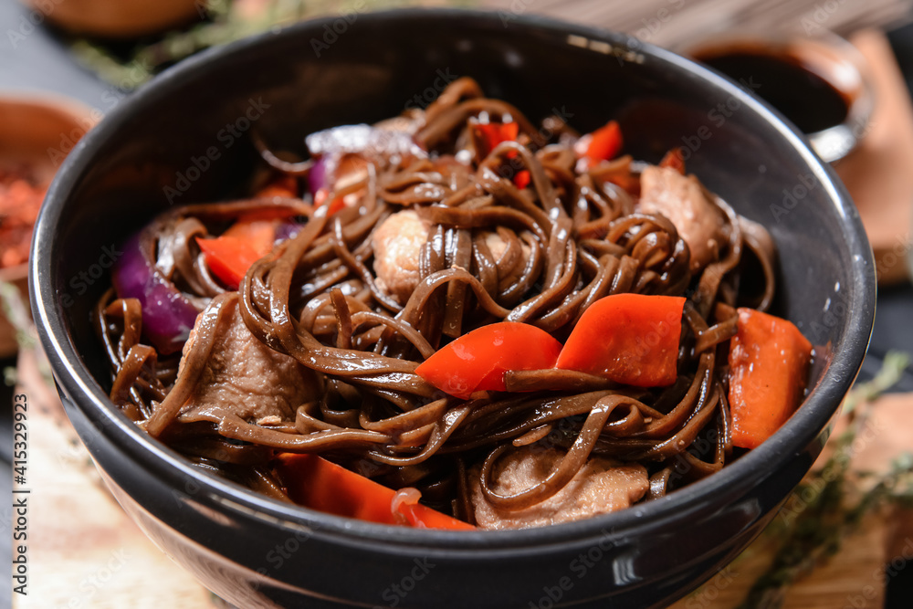 Plate with tasty soba noodles and meat on dark background Plate with tasty soba noodles and meat on dark background