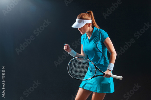 Tennis player with racket in blue costume. Woman athlete playing on black background. © Mike Orlov