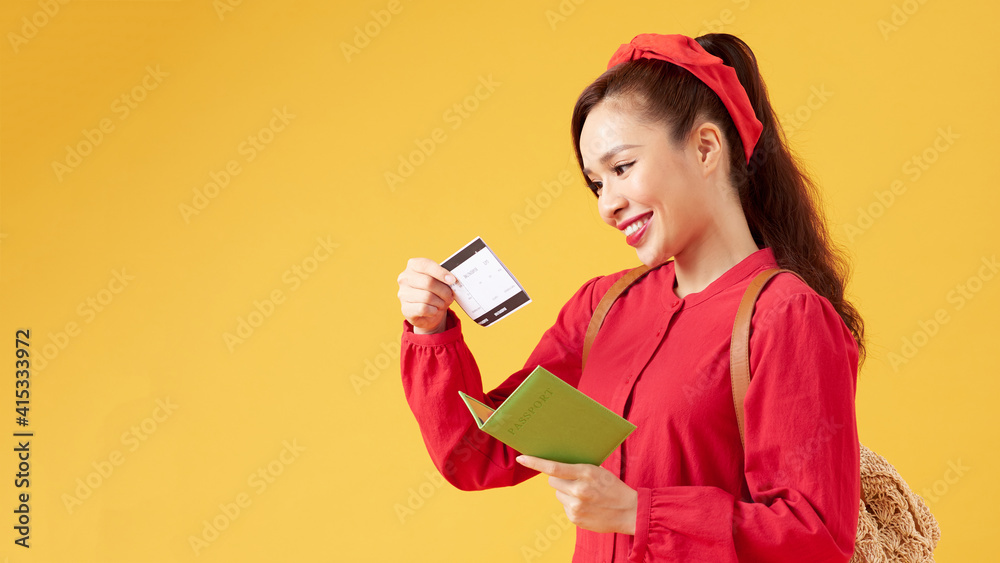Cheerful girl holding passport, plane ticket and passport before yellow background, Cheerful girl holding passport, plane ticket and passport before yellow background,