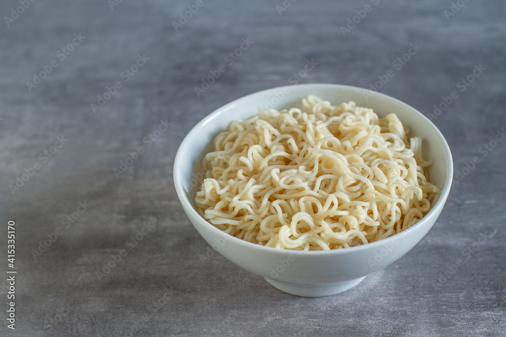 Pre-cooked ramen noodles in an white bowl on a gray background Pre-cooked ramen noodles in an white bowl on a gray background