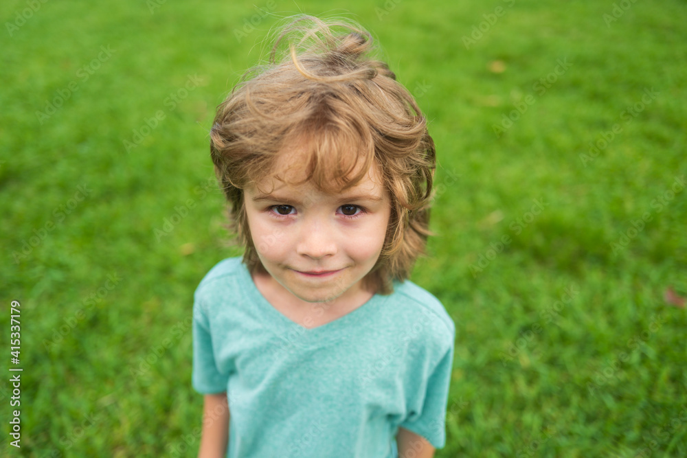 Closeup attractive laughing boy. Child emotions concept. Portrait of young smiling kid outdoor. Grass background. Closeup attractive laughing boy. Child emotions concept. Portrait of young smiling kid outdoor. Grass background.