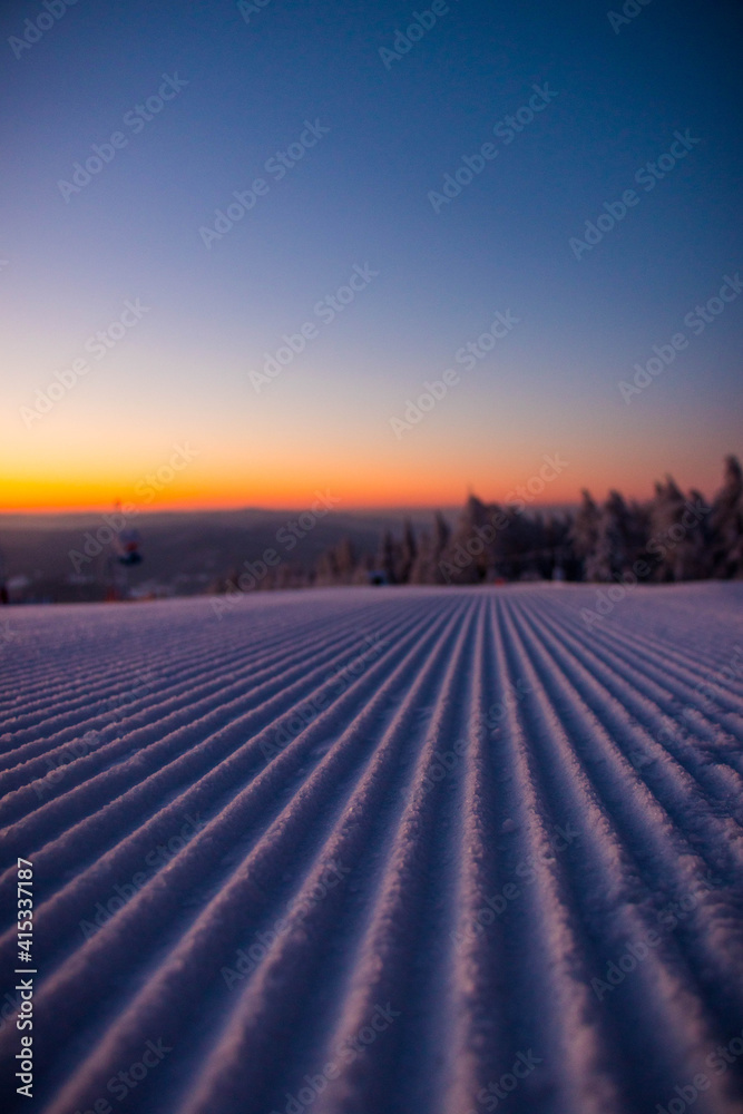 
sunrise on a ski slope in the snowy mountains