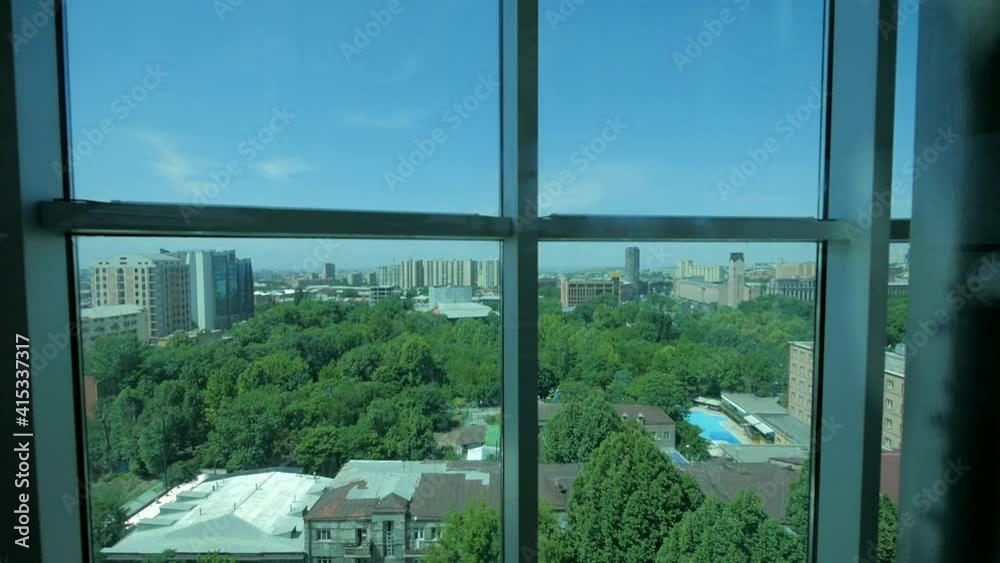 View of the city from a skyscraper glass elevator descending inside a business center with a glass roof. Elevator inside modern corporate office building, city center scenery - Slow Motion