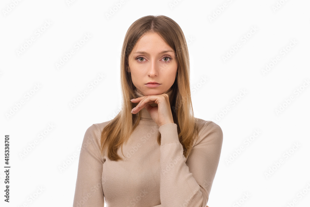 Pensive blond girl with thoughtful expression, keeps hand on chin, plans something or makes choice