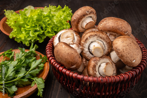 mushrooms in a basket with lettuce and herbs on a dark wooden background