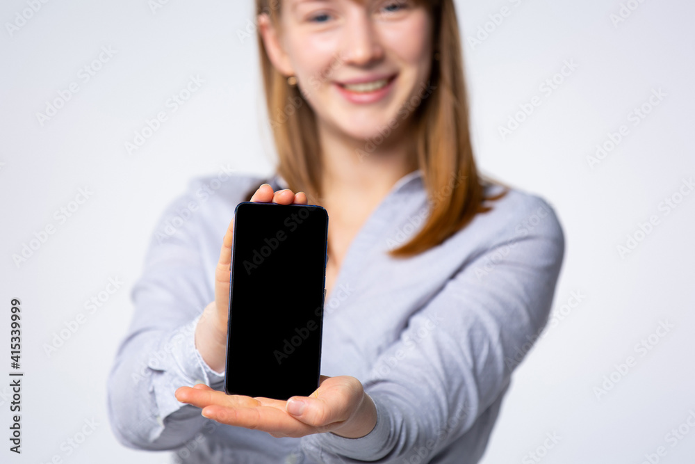 Selective focus of beautiful blonde woman, consultant , and showing smartphone a where you can enter your information. Marketing concept and online shopping. Selective focus of beautiful blonde woman, consultant , and showing smartphone a where you can enter your information. Marketing concept and online shopping.