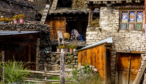 nepali woman dressed in traditional clothing works in a house in a nepal village