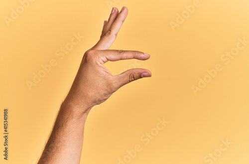 Fotografie Arm and hand of caucasian man over yellow isolated background picking and taking