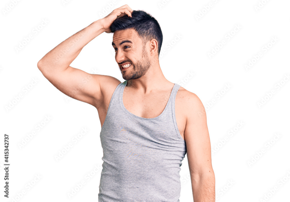 Young handsome man wearing swimwear and sleeveless t-shirt smiling confident touching hair with hand up gesture, posing attractive and fashionable Young handsome man wearing swimwear and sleeveless t-shirt smiling confident touching hair with hand up gesture, posing attractive and fashionable