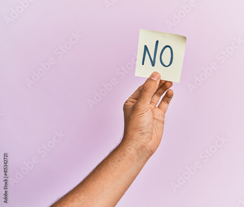 Hand of hispanic man holding no reminder paper over isolated pink background.