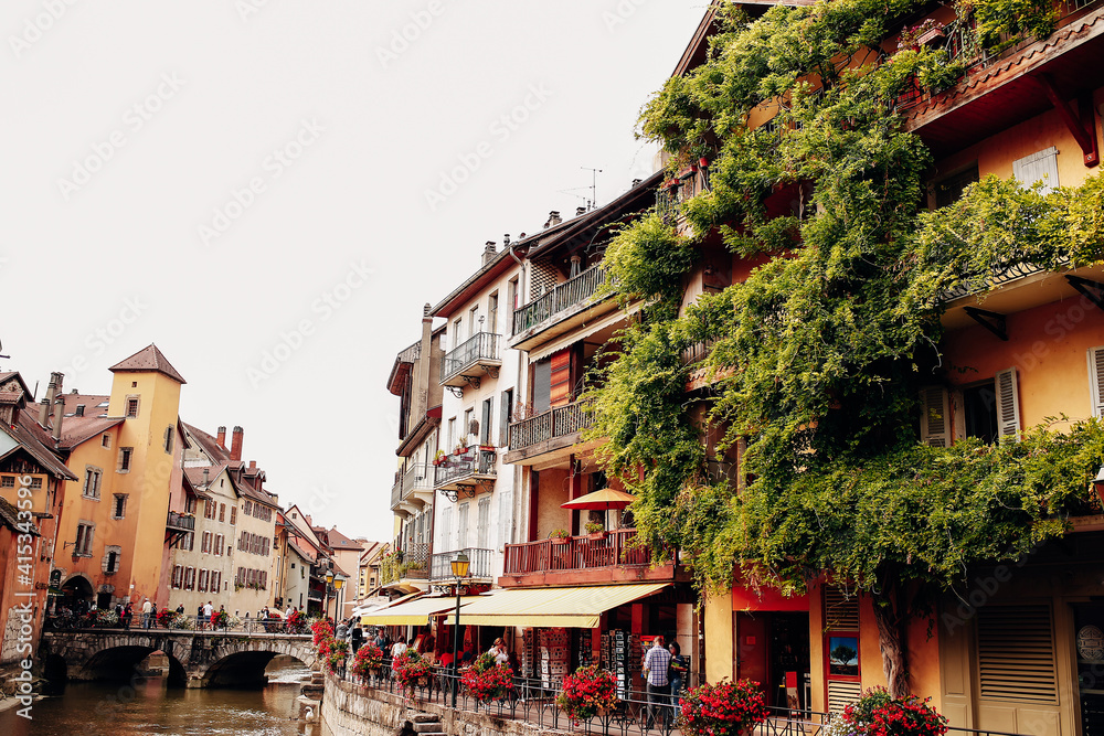 Annecy city water channel, red flowers, old buildings, bridge, green balconies