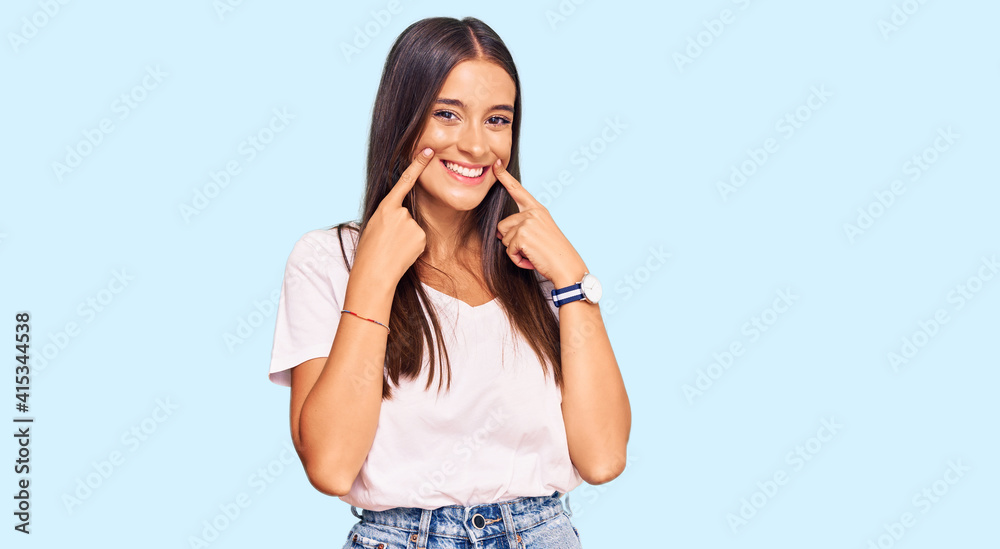 Young hispanic woman wearing casual white tshirt smiling with open mouth, fingers pointing and forcing cheerful smile Young hispanic woman wearing casual white tshirt smiling with open mouth, fingers pointing and forcing cheerful smile