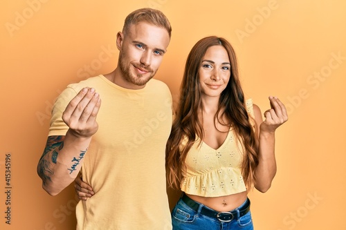 Young couple of girlfriend and boyfriend hugging and standing together doing money gesture with hands, asking for salary payment, millionaire business