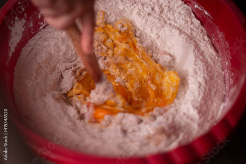 mixing flour with egg and milk by the housewife. preparing ingredients for traditional homemade cakes