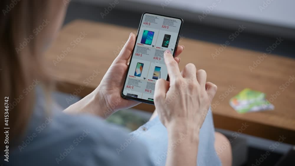 A woman is shopping online from home. A housewife chooses a smartphone in an online store.