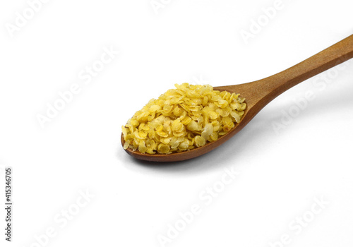 Millet flakes in a wooden spoon isolated on white bacground.