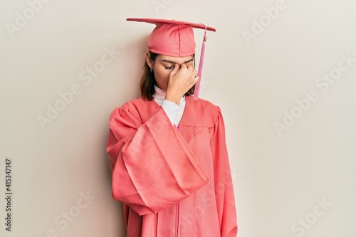 Young caucasian woman wearing graduation cap and ceremony robe tired rubbing nose and eyes feeling fatigue and headache. stress and frustration concept.