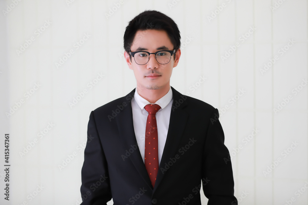 Portrait of young and cute Asian man wearing black suit and eyeglasses pose to camera with self-confidence and friendly face Portrait of young and cute Asian man wearing black suit and eyeglasses pose to camera with self-confidence and friendly face