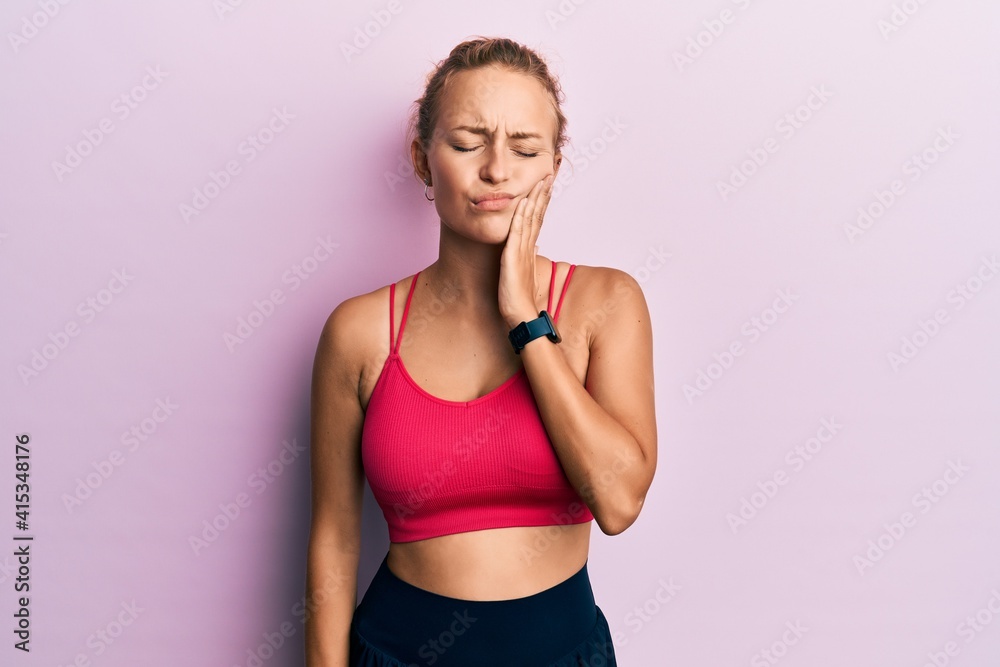 Beautiful caucasian woman wearing sportswear touching mouth with hand with painful expression because of toothache or dental illness on teeth. dentist Beautiful caucasian woman wearing sportswear touching mouth with hand with painful expression because of toothache or dental illness on teeth. dentist