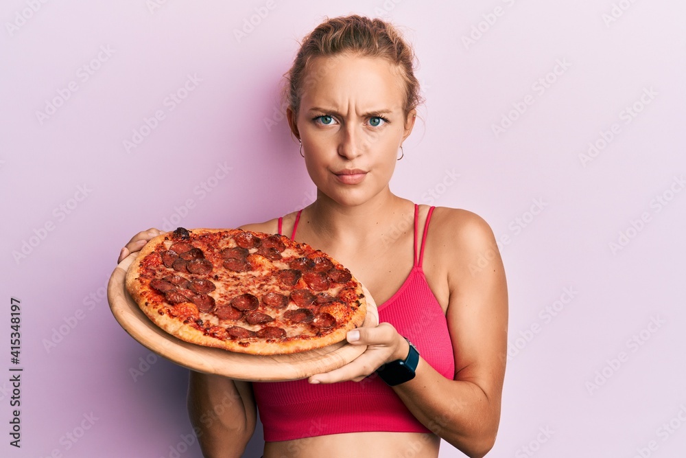 Beautiful caucasian woman holding italian pizza skeptic and nervous, frowning upset because of problem. negative person. Beautiful caucasian woman holding italian pizza skeptic and nervous, frowning upset because of problem. negative person.