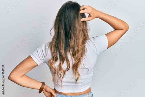 Young brunette woman wearing casual white t shirt backwards thinking about doubt with hand on head