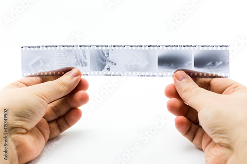 hands holding 35mm photographic film negatives on white background