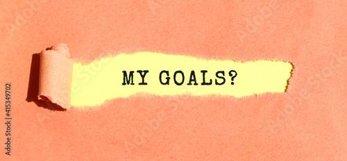 The text MY GOALS appearing on yellow paper behind torn color paper. Top view.