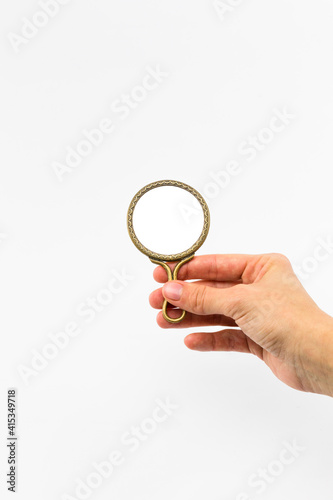 hand holding a small round mirror on white background