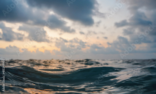 Sea surface, abstract closeup low angle view from swimming person point of view, morning overcast sky background