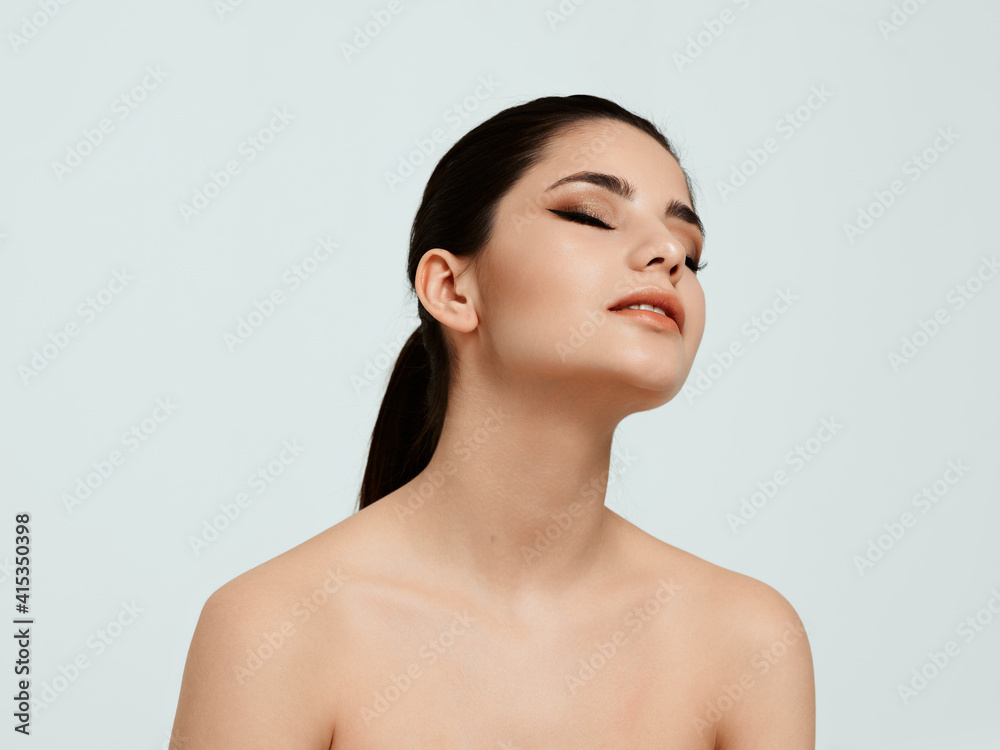 attractive woman with bare shoulders on a light background looks to the side attractive woman with bare shoulders on a light background looks to the side