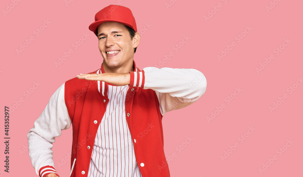 Handsome caucasian man wearing baseball uniform gesturing with hands showing big and large size sign, measure symbol. smiling looking at the camera. measuring concept.
