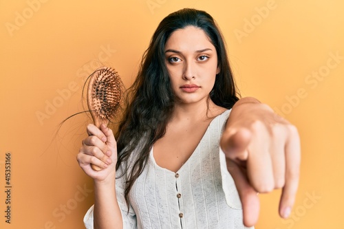 Canvas Print Beautiful middle eastern woman holding comb loosing hair pointing with finger to