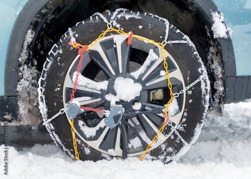 snow chains fitted on a car wheel in winter