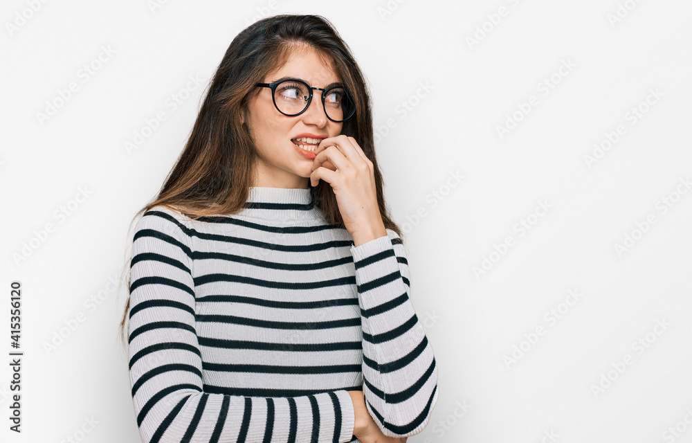 Young beautiful teen girl wearing casual clothes and glasses looking stressed and nervous with hands on mouth biting nails. anxiety problem. Young beautiful teen girl wearing casual clothes and glasses looking stressed and nervous with hands on mouth biting nails. anxiety problem.