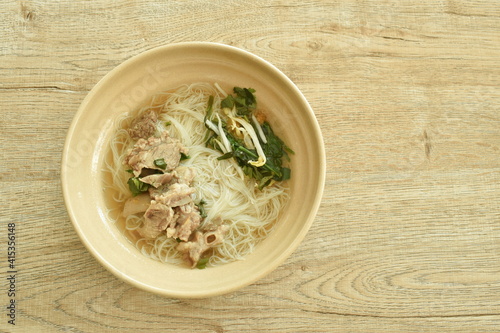 boiled vermicelli thin rice noodles topping  slice braised pork in herb brown soup on bowl