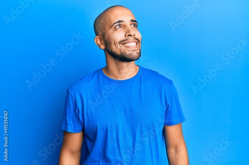Hispanic adult man wearing casual blue t shirt looking to side, relax profile pose with natural face and confident smile. © Krakenimages.com