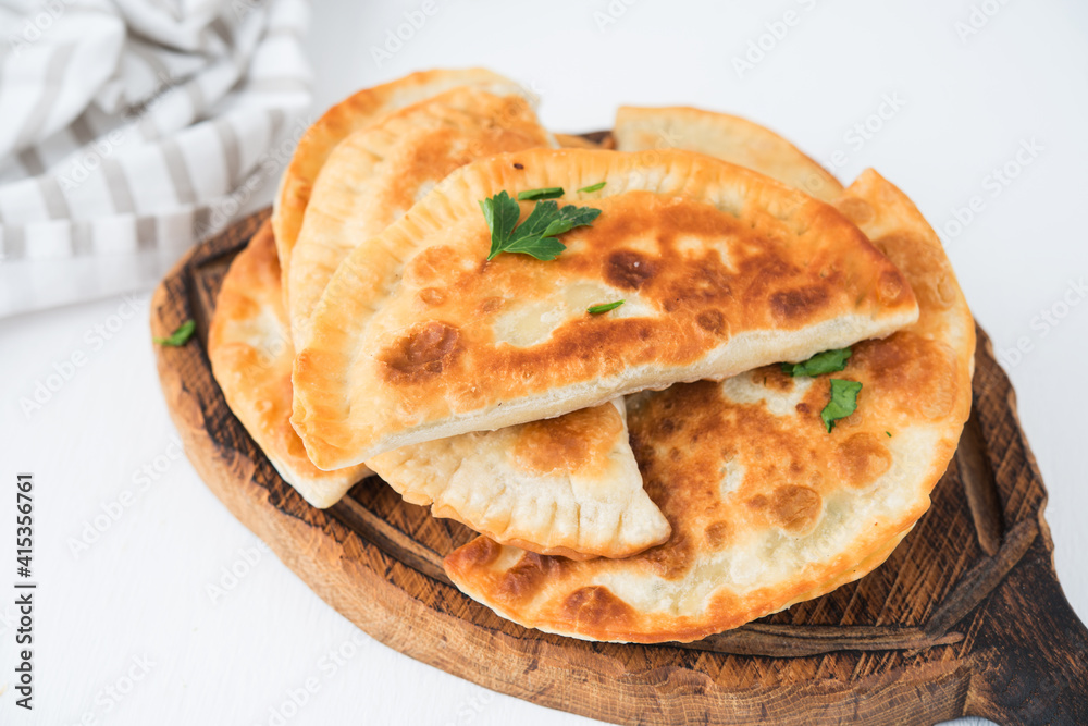 Homemade fried empanadas with pork, chebureks with mushrooms on a wooden board Homemade fried empanadas with pork, chebureks with mushrooms on a wooden board