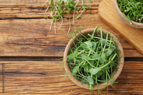 Fresh microgreen on wooden table, flat lay. Space for text