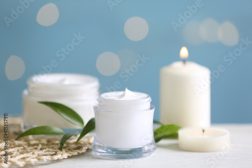 Beautiful spa composition with cosmetic products and candles on white table, closeup