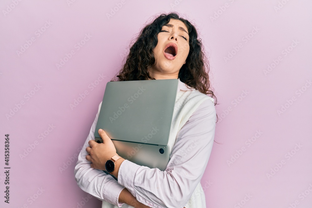 Young brunette woman with curly hair hugging laptop with love angry and mad screaming frustrated and furious, shouting with anger looking up. Young brunette woman with curly hair hugging laptop with love angry and mad screaming frustrated and furious, shouting with anger looking up.