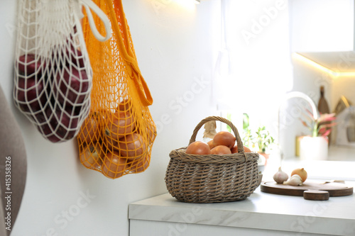 Basket with golden onions on countertop in kitchen