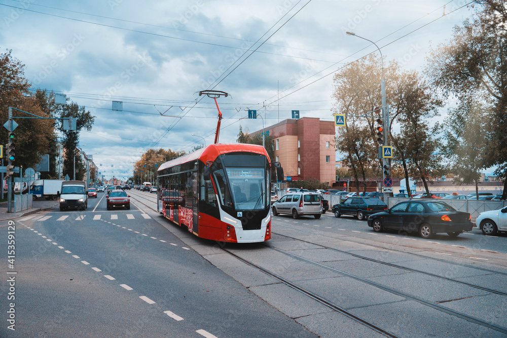 Fototapeta premium Red and white modern tram on the street in Perm, Russia. New trams for Russian cities.